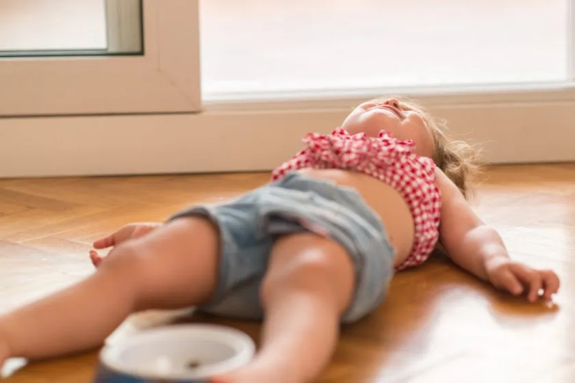 Beautiful blond child crying and shouting with tantrum laying on the floor at home.