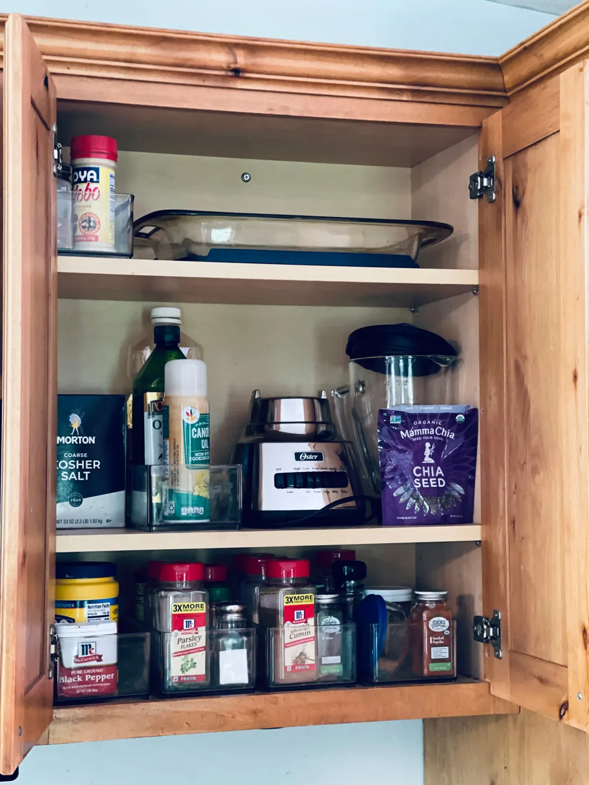 minimalist kitchen cabinet full of spices, blender and a 9x13 casserole dish.