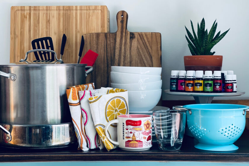 minimalist kitchen essentials arranged on counter: pots, cutting boards, dishes, colander.