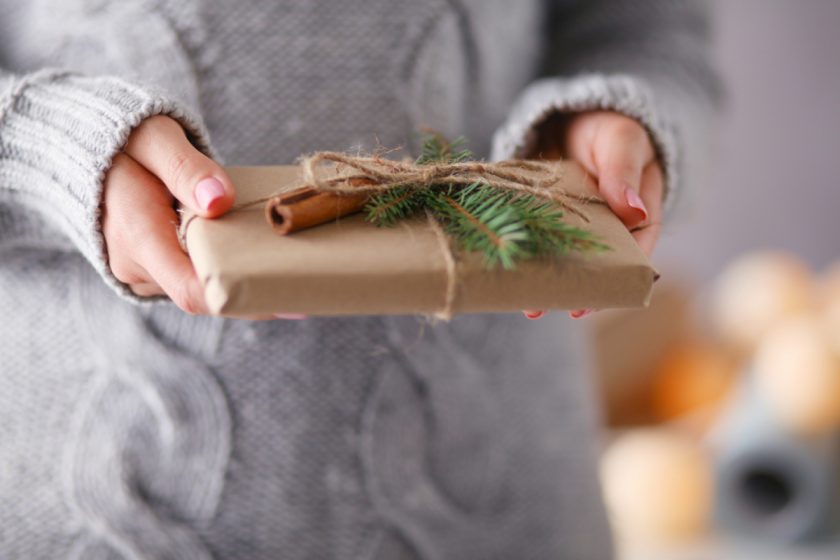 mom handing small, naturally wrapped gift to her child, focus on gift in hands
