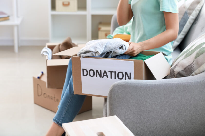 Young woman decluttering and putting clothes for donation in box