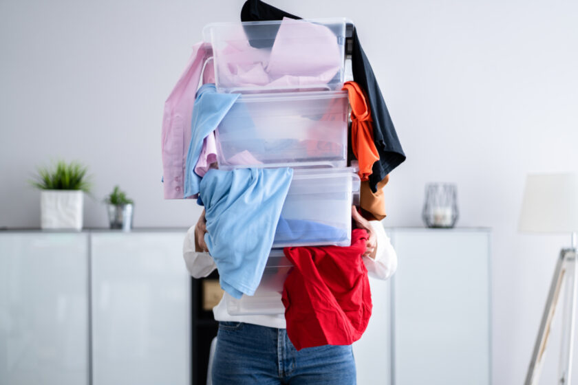 minimalist woman holding three clear bins full of clothing donations