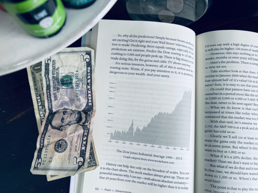 Picture of Graph of US Stock Market Performance Over Time in book, A Simple Path to Wealth, with cash nearby