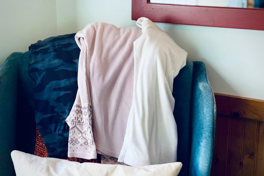 three pieces from minimalist winter wardrobe draped over blue armchair