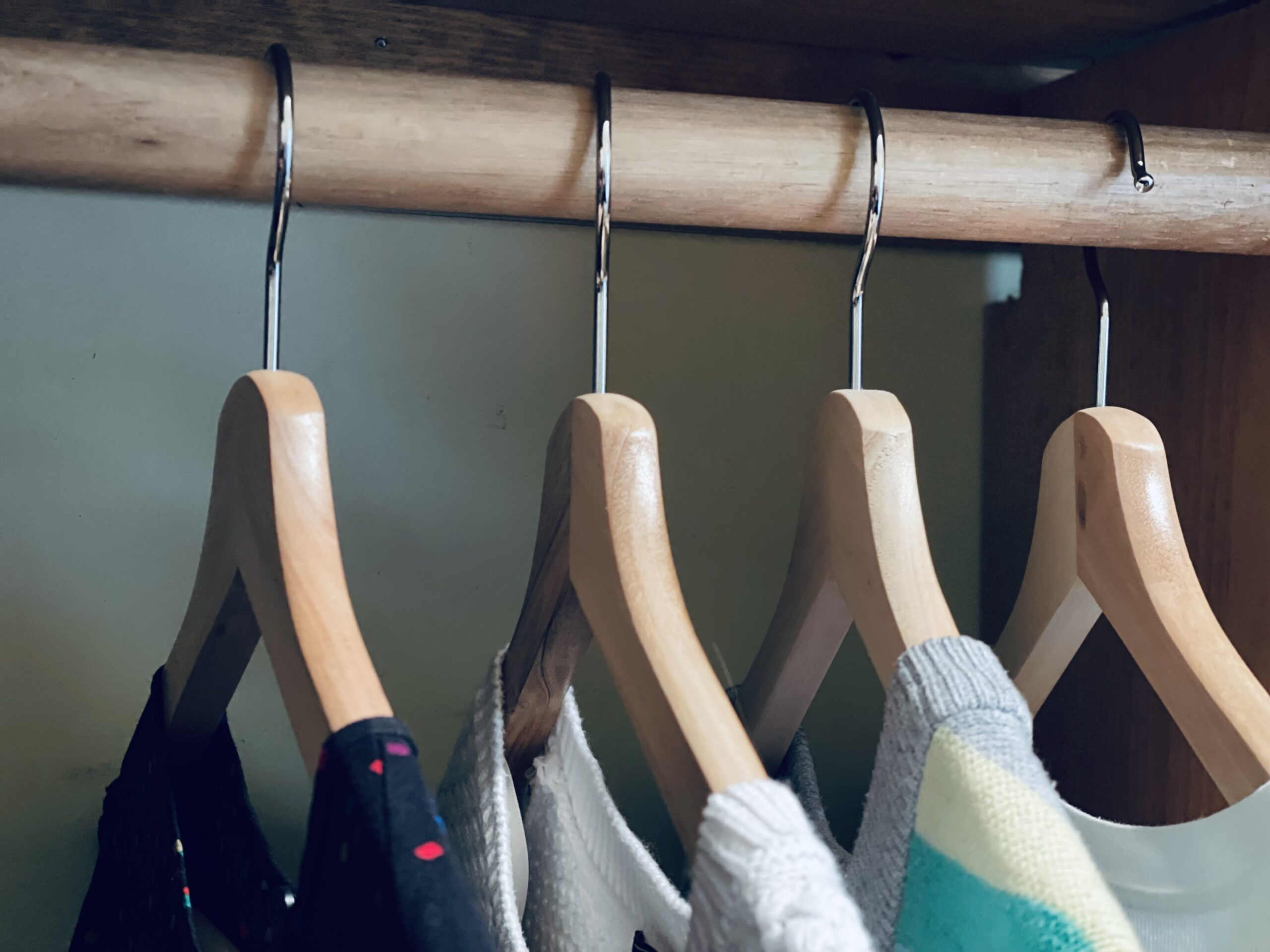 four clothes hangers on closet rack, with emphasis on one "backwards" hanger