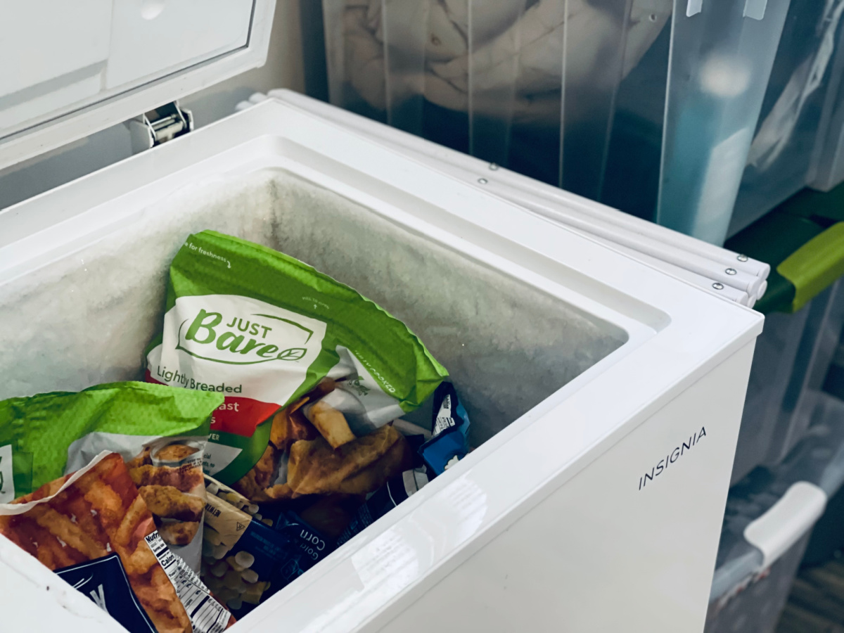 deep freezer open, showing frozen chicken strips and french fries