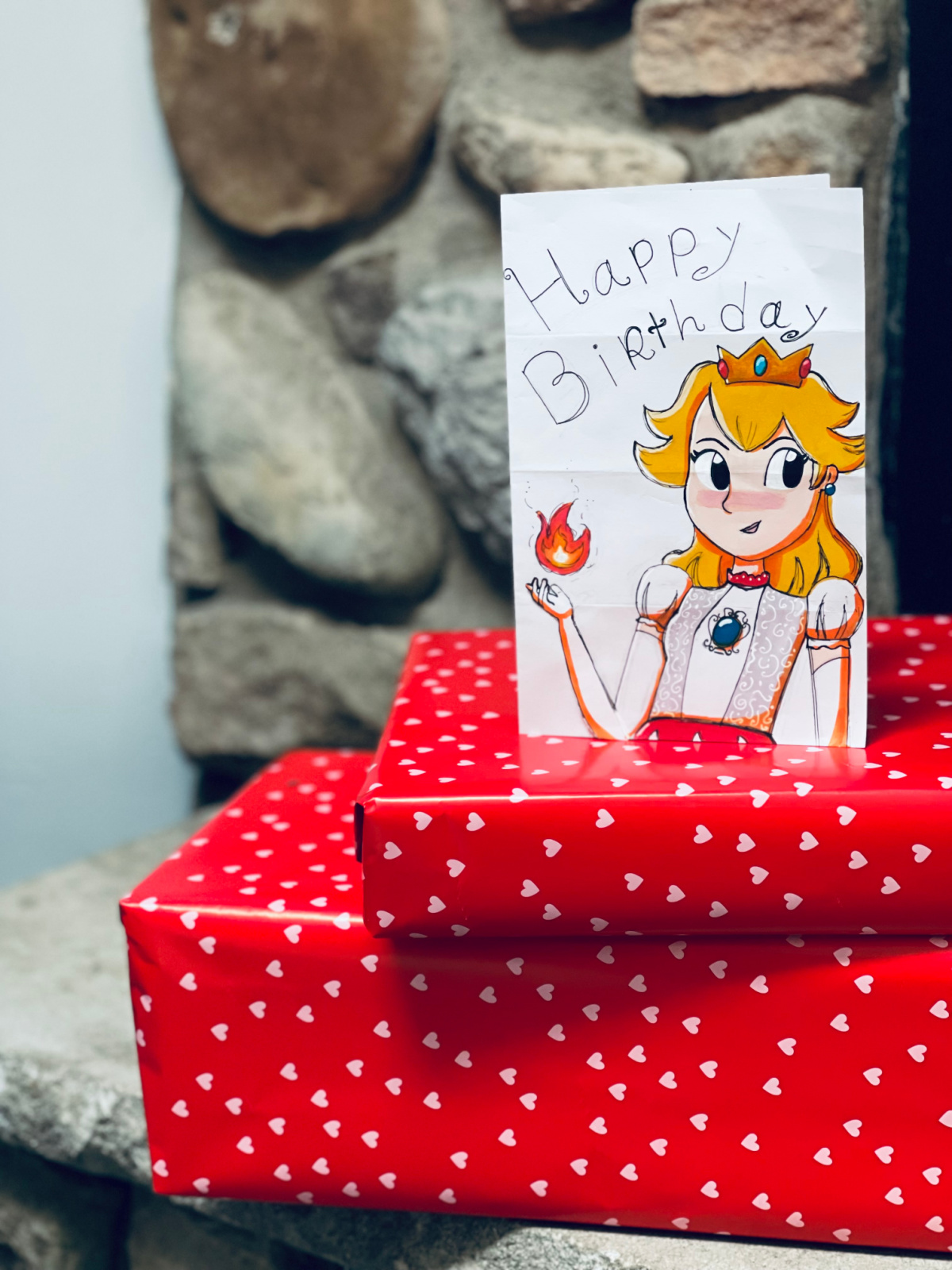 two birthday presents wrapped in red heart paper with Princess Peach birthday card on top