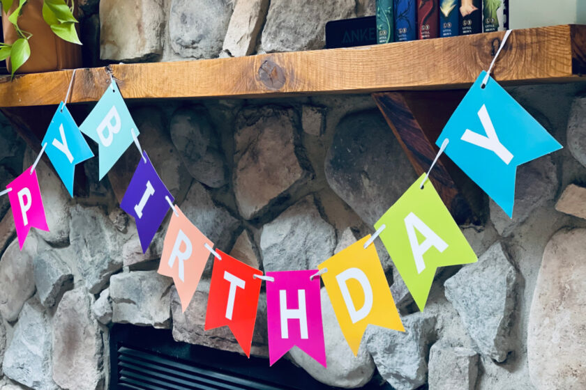 colorful happy birthday banner hanging on mantle over fireplace
