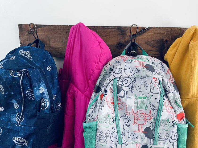 school backpacks and sweatshirts hanging on rack