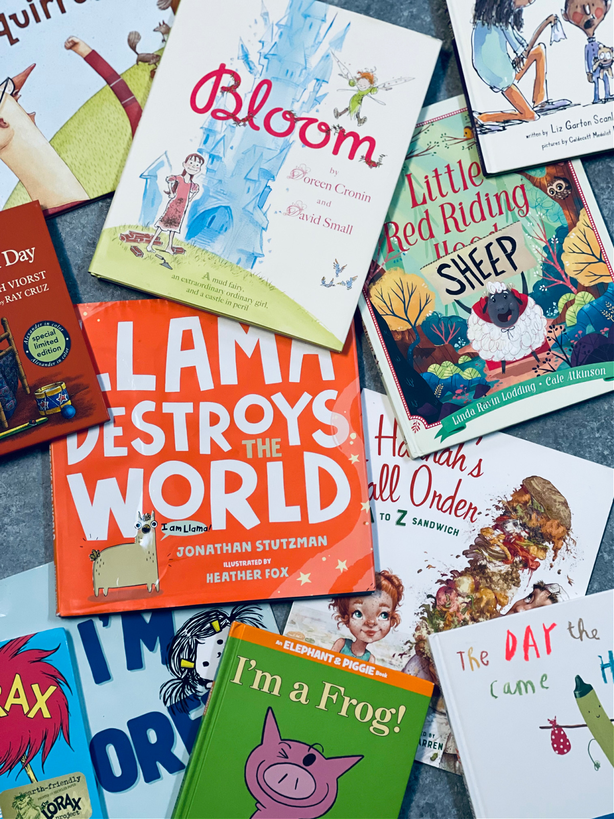 favorite picture books spread out on a surface, including Bloom, Llama Destroys the World and I'm a Frog!