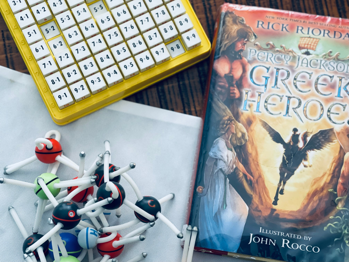 strewing on a table: addition machine, Percy Jackson Greek Heroes book and Happy Atoms