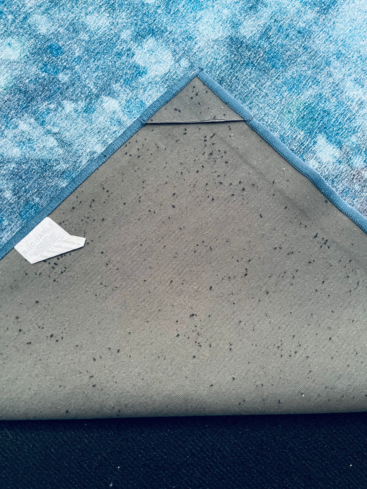 black particles from Ruggable rug pad shown on back of Ruggable rug