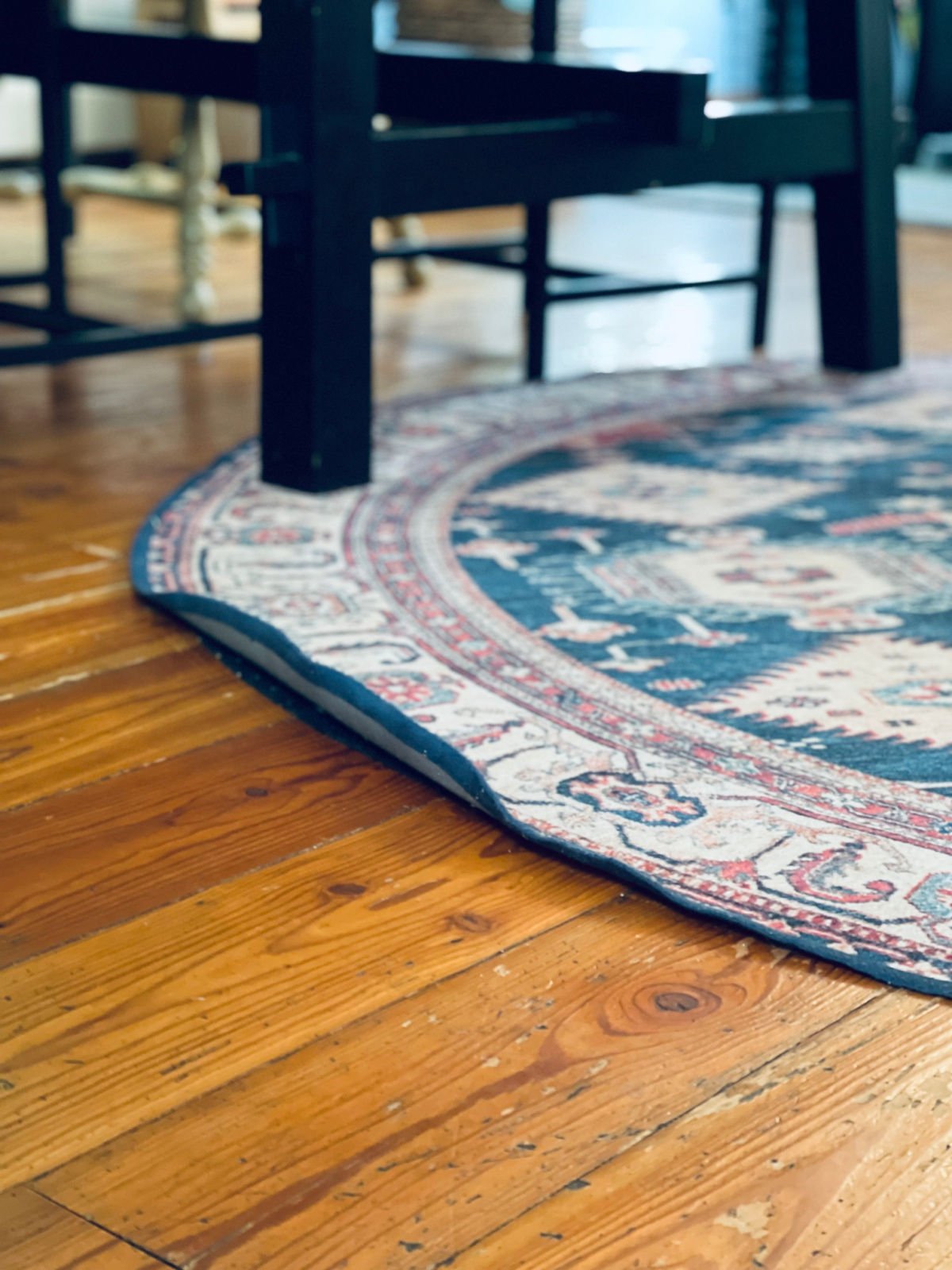 curling edge of Ruggable rug in focus, underneath dining room table.