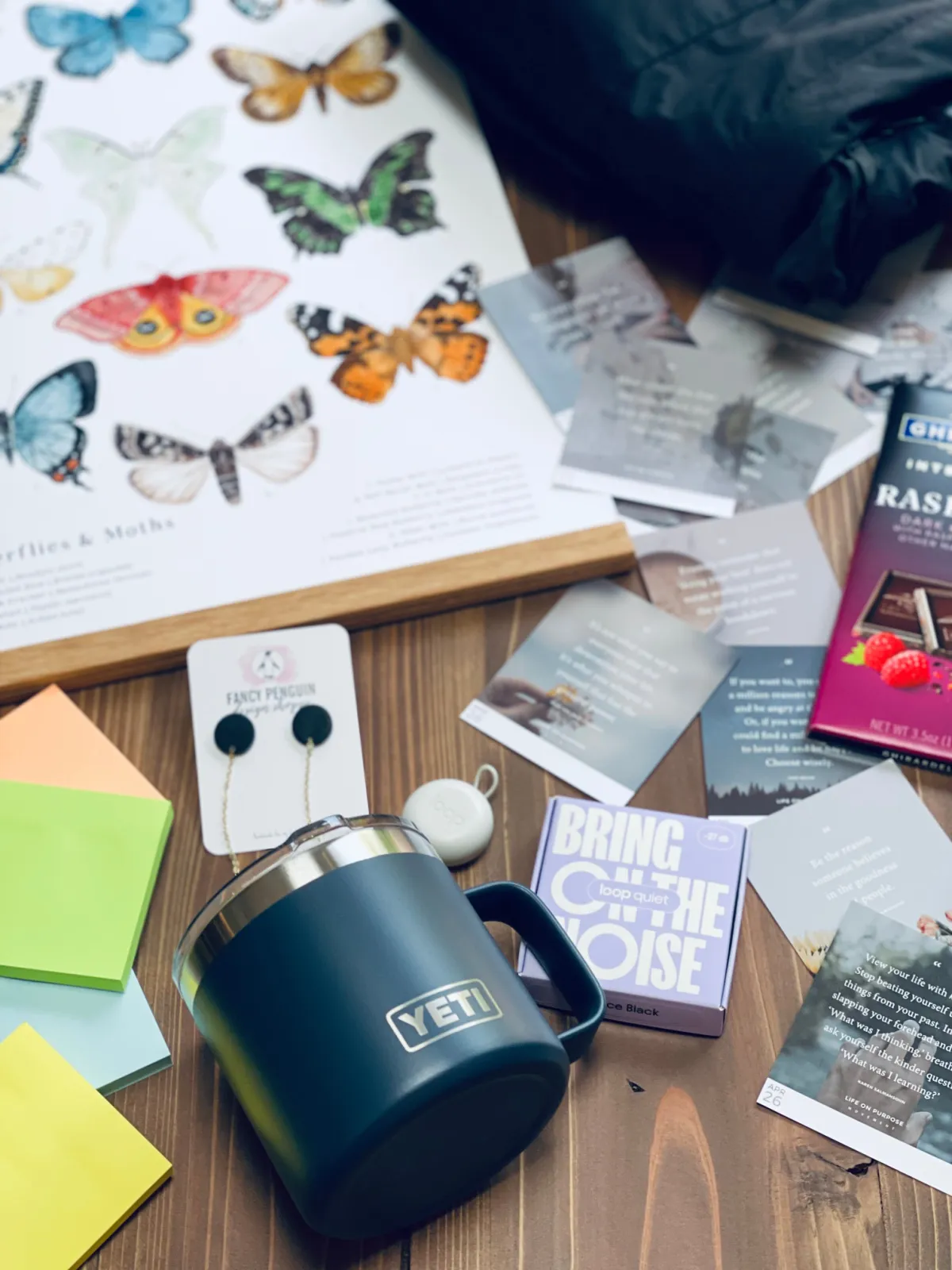 gift for homeschool moms spread out on table - Yeti mug, Twig & Moth butterfly poster, Ghiradelli chocolate, loop earplugs and post-it notes.