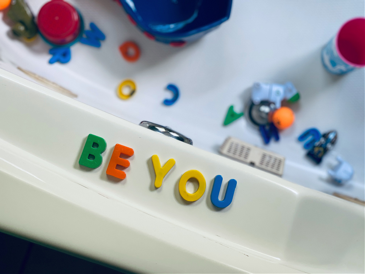 letters spelling "be you" on bathtub ledge