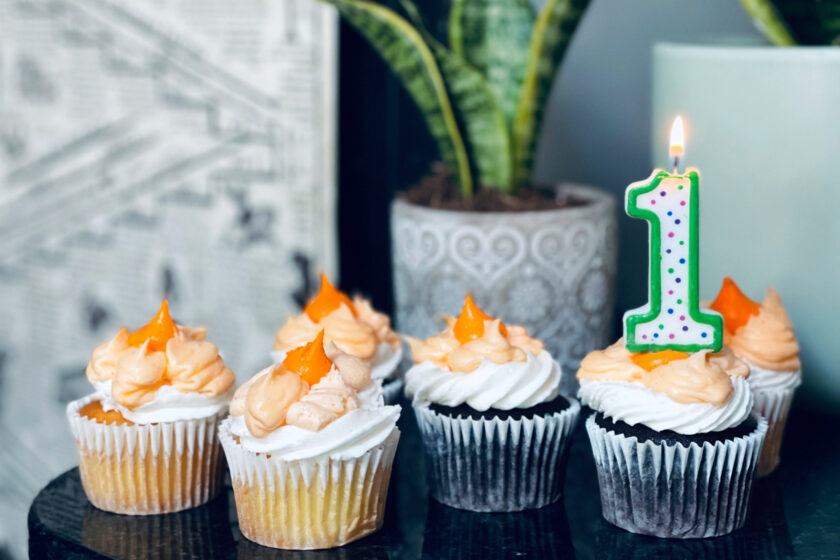 cupcakes on counter with a lit "1" candle in far right cupcake for 1-year-old birthday.