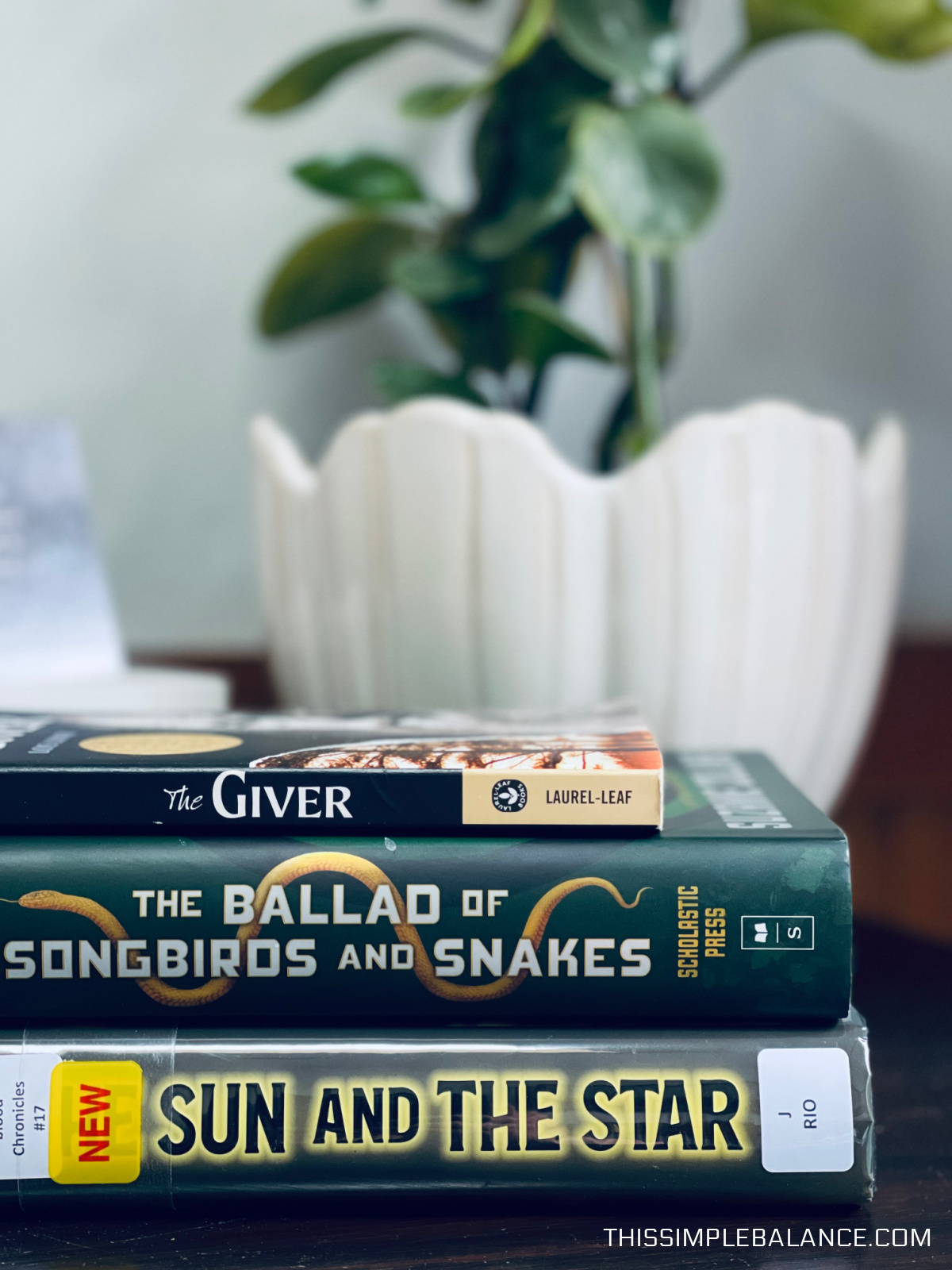 The Giver, The Ballad of Songbirds and Snakes and The Sun and the Star books on a table.