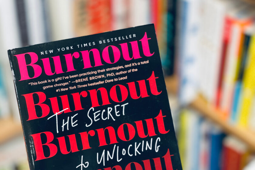 Emily and Amelia Nagoski's book Burnout - cover in focus with bookshelves in the background.