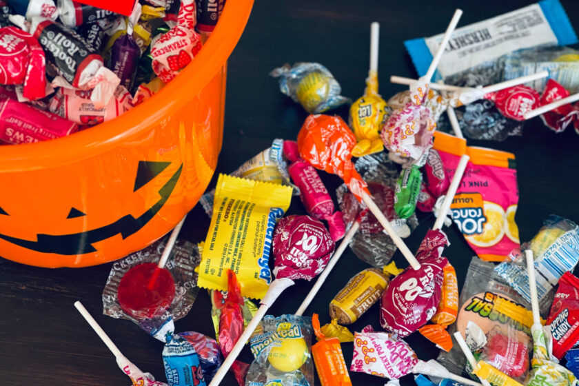 Halloween candy in orange bucket and spread out on table.