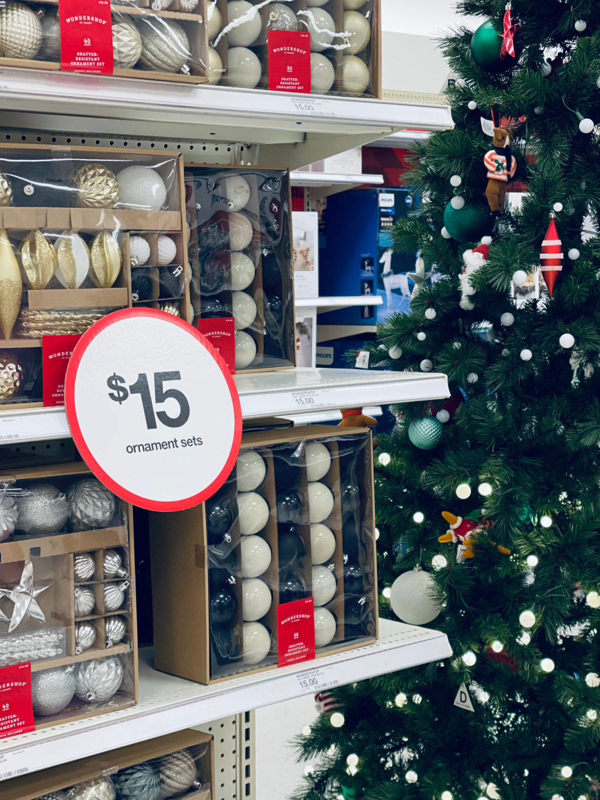 Christmas ornament sets in store marked $15 next to a decorated Christmas tree.