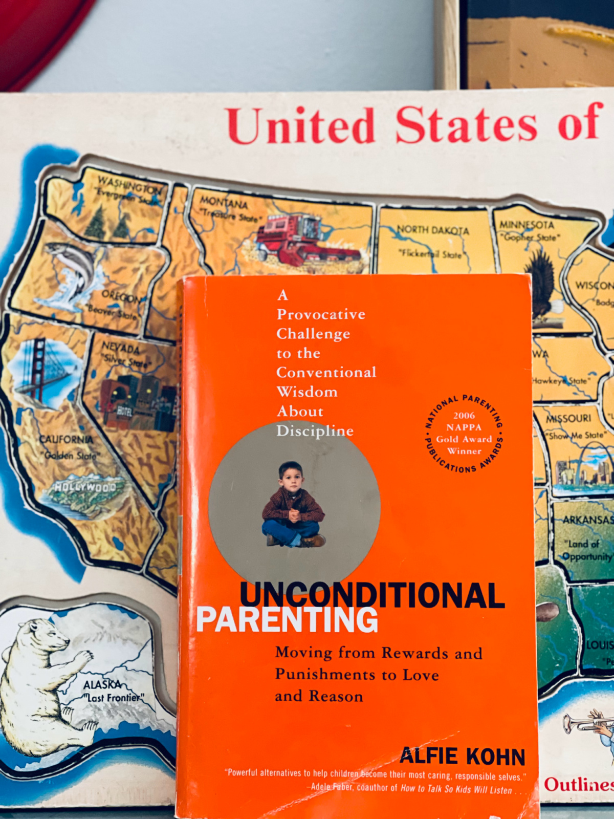 Unconditional Parenting book by Alfie Kohn in front of United States puzzle.