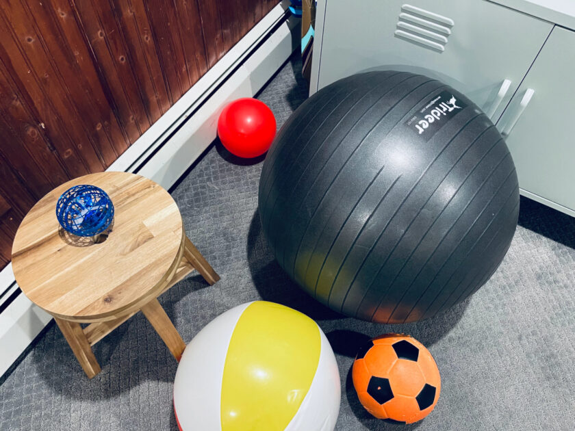 a collection of indoor balls, including a beach ball, soccer ball, exercise ball and small bouncy ball.
