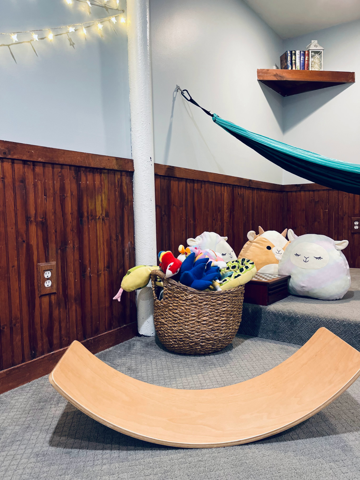 balance board in minimalist playroom, with stuffed animal basket and squishmallows nearby.
