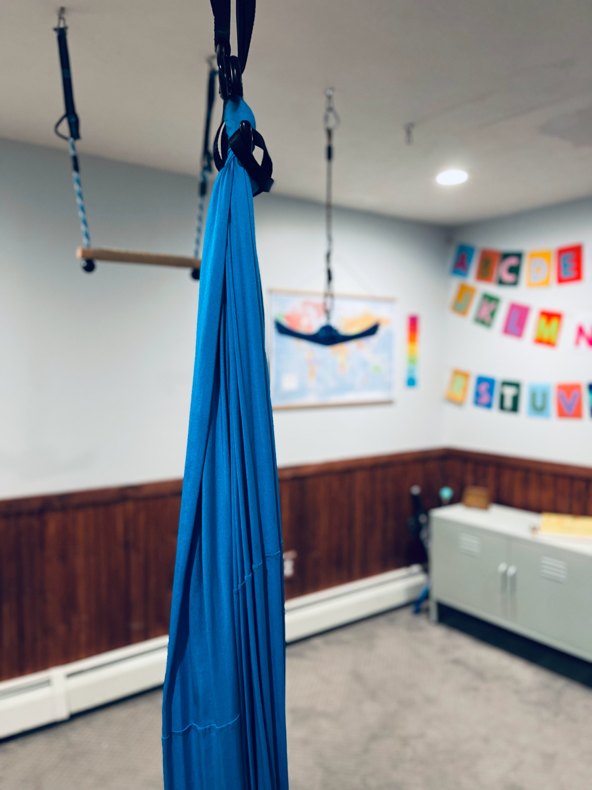 sensory swing in playroom with ninja rings and alphabet banner in background.