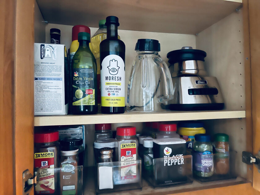 spices and oils and blender on cabinet pantry shelves.