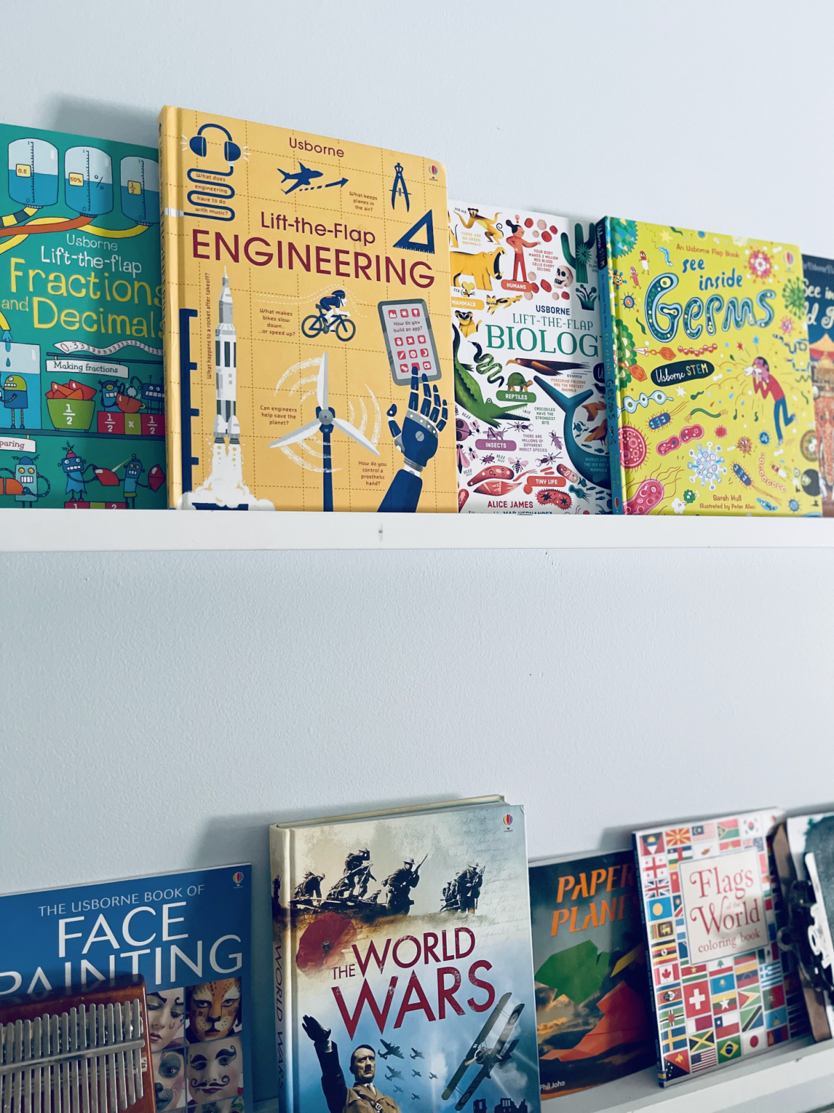 colorful life the flap books and other books on narrow IKEA white wall shelves.