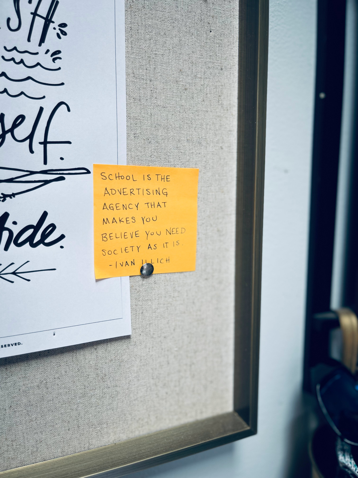 Ivan Illich quote on a post-it on bulletin board, "School is the advertising agency that makes you believe you need society as it is."