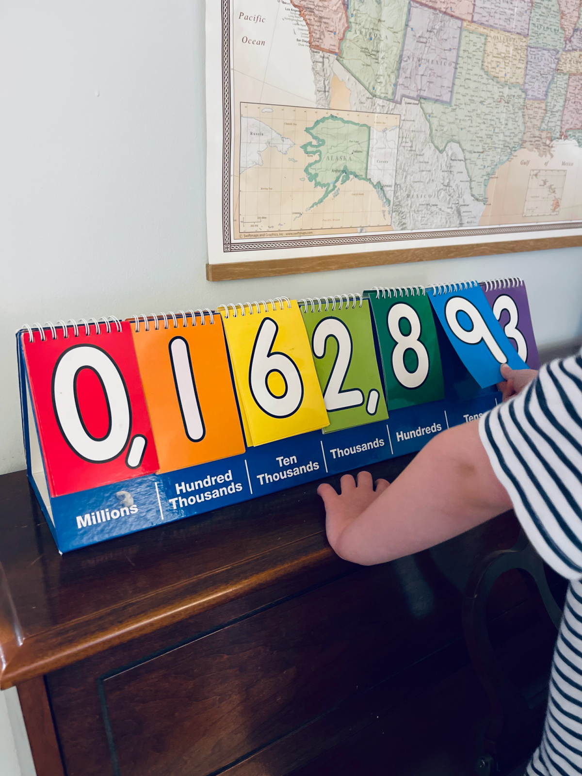 child flipping numbers on a colorful place value chart.