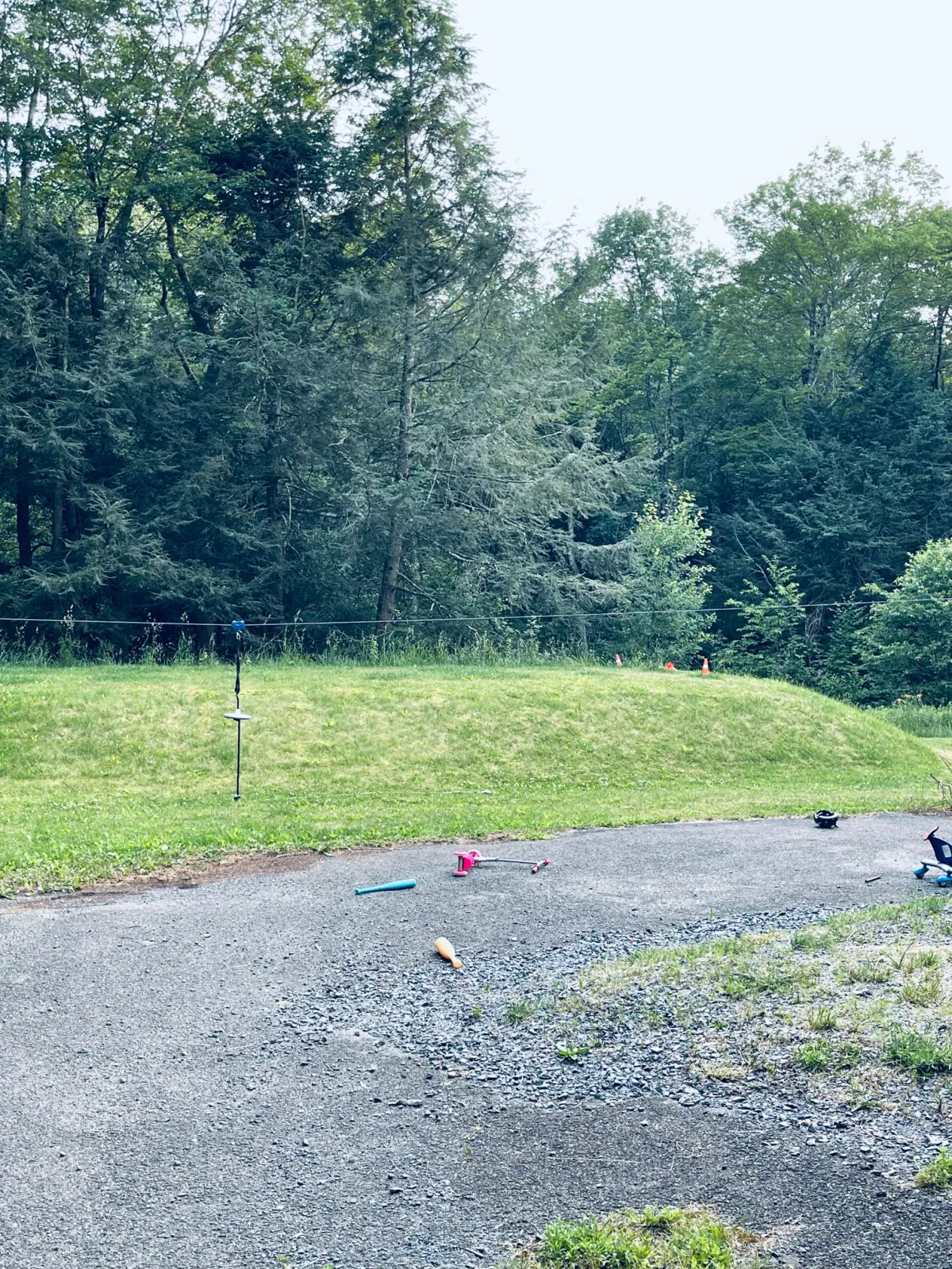 backyard septic hill with zipline and scooters scattered.
