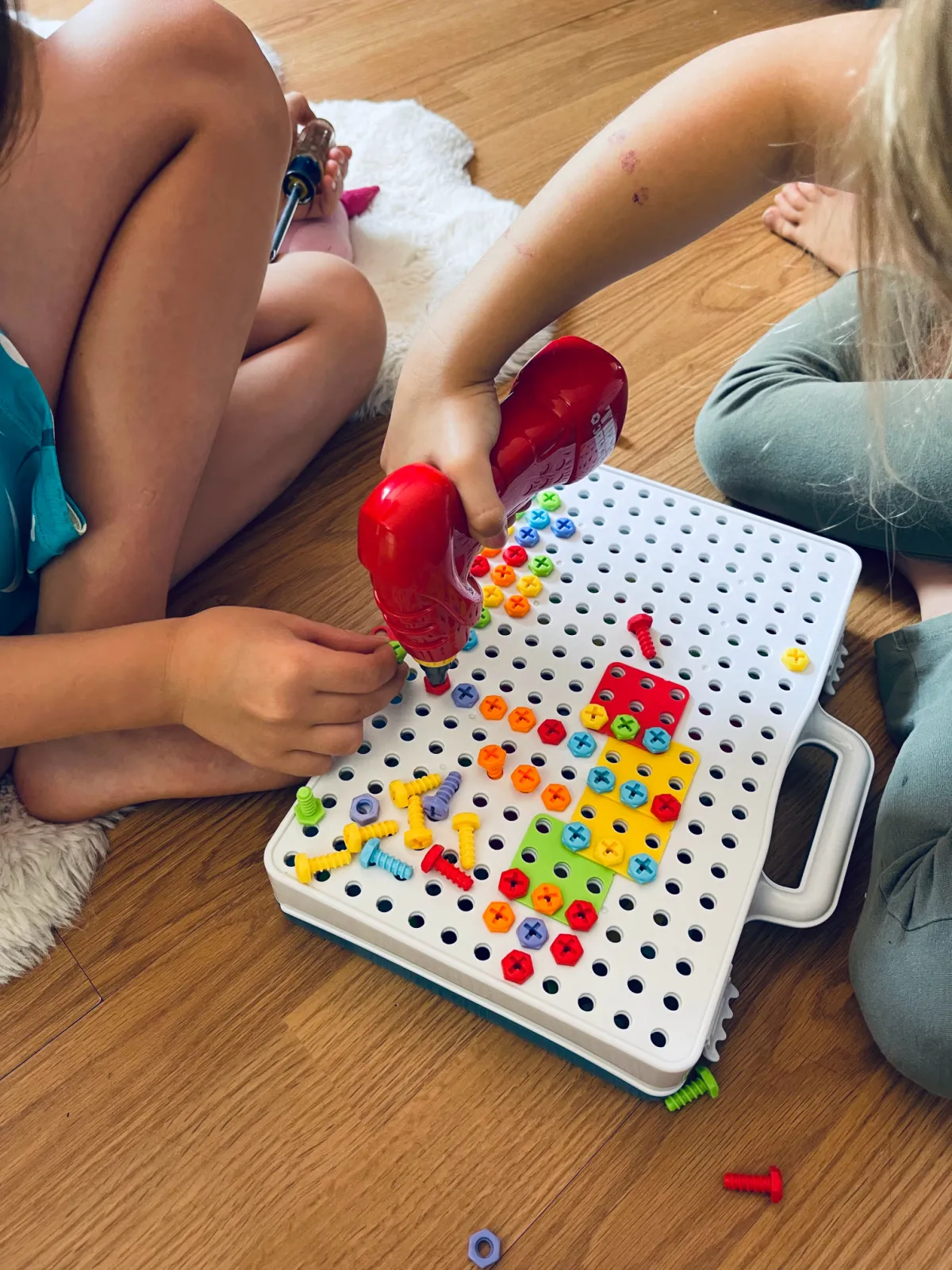 unschooled kids playing with a drill and colorful tool kit.
