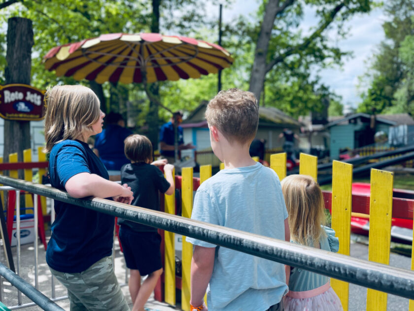 Homeschooled siblings standing in line waiting for amusement park ride.