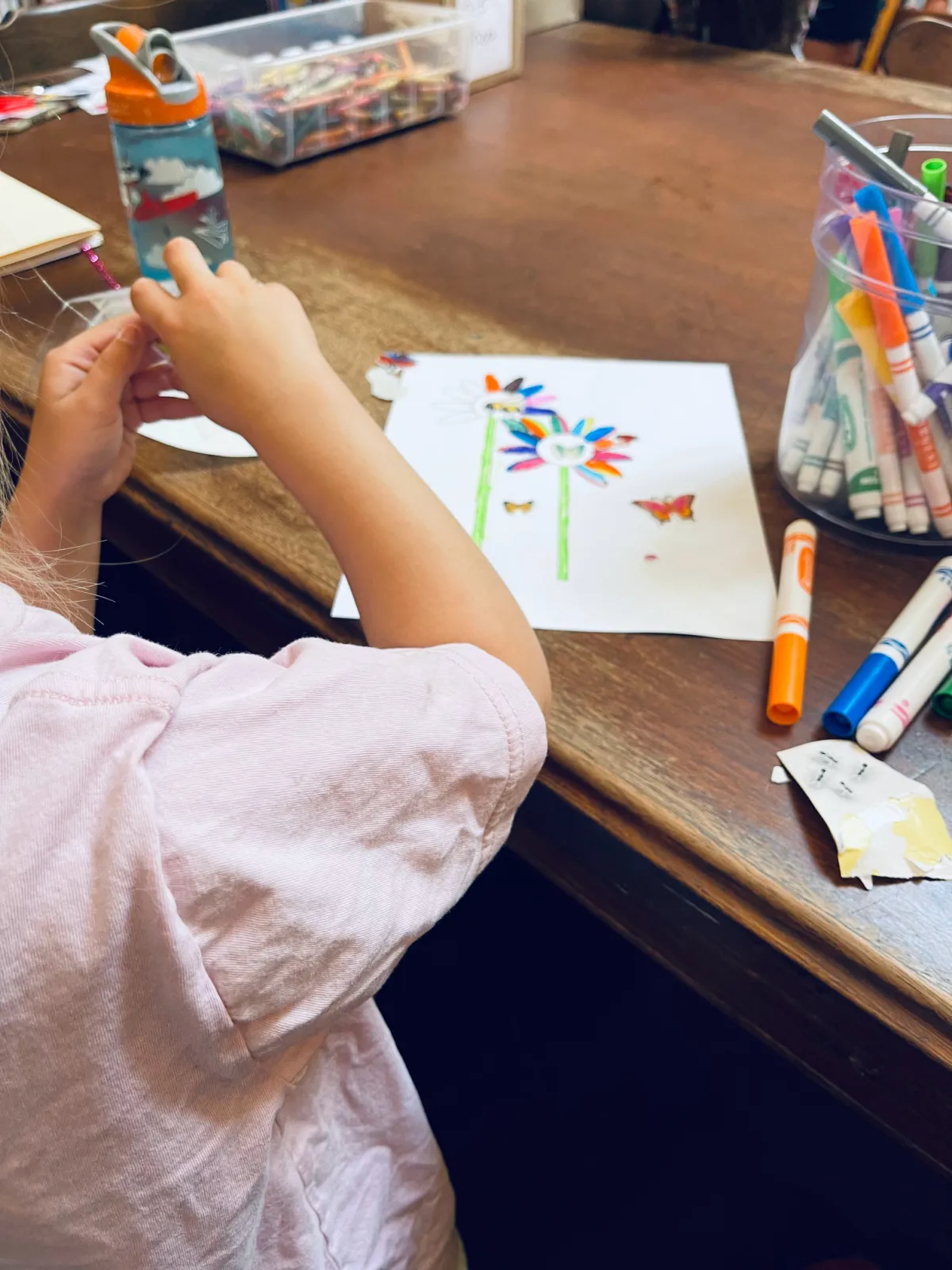 young homeschooled child drawing with markers at library table after story hour.