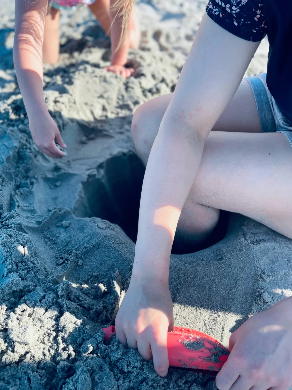 unschooled kids digging in the sand during a beach vacation.
