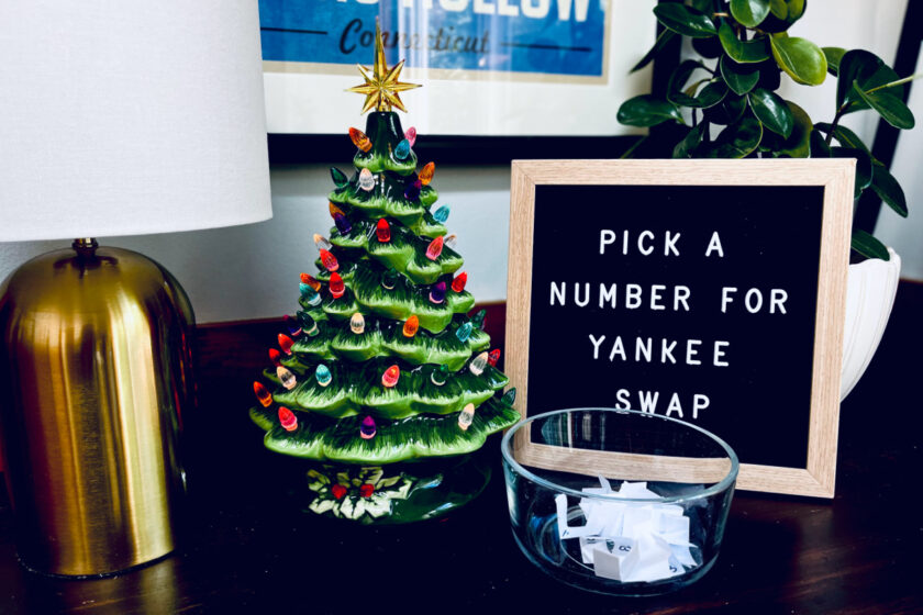 letter board that says "pick a number for yankee swap" next to plug in Christmas tree