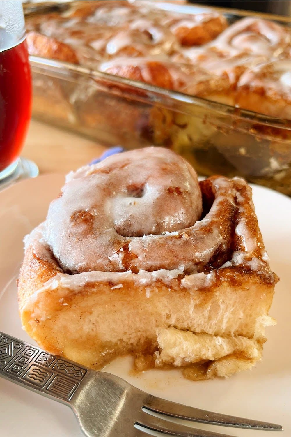 cinnamon roll on white plate with fork beside it.