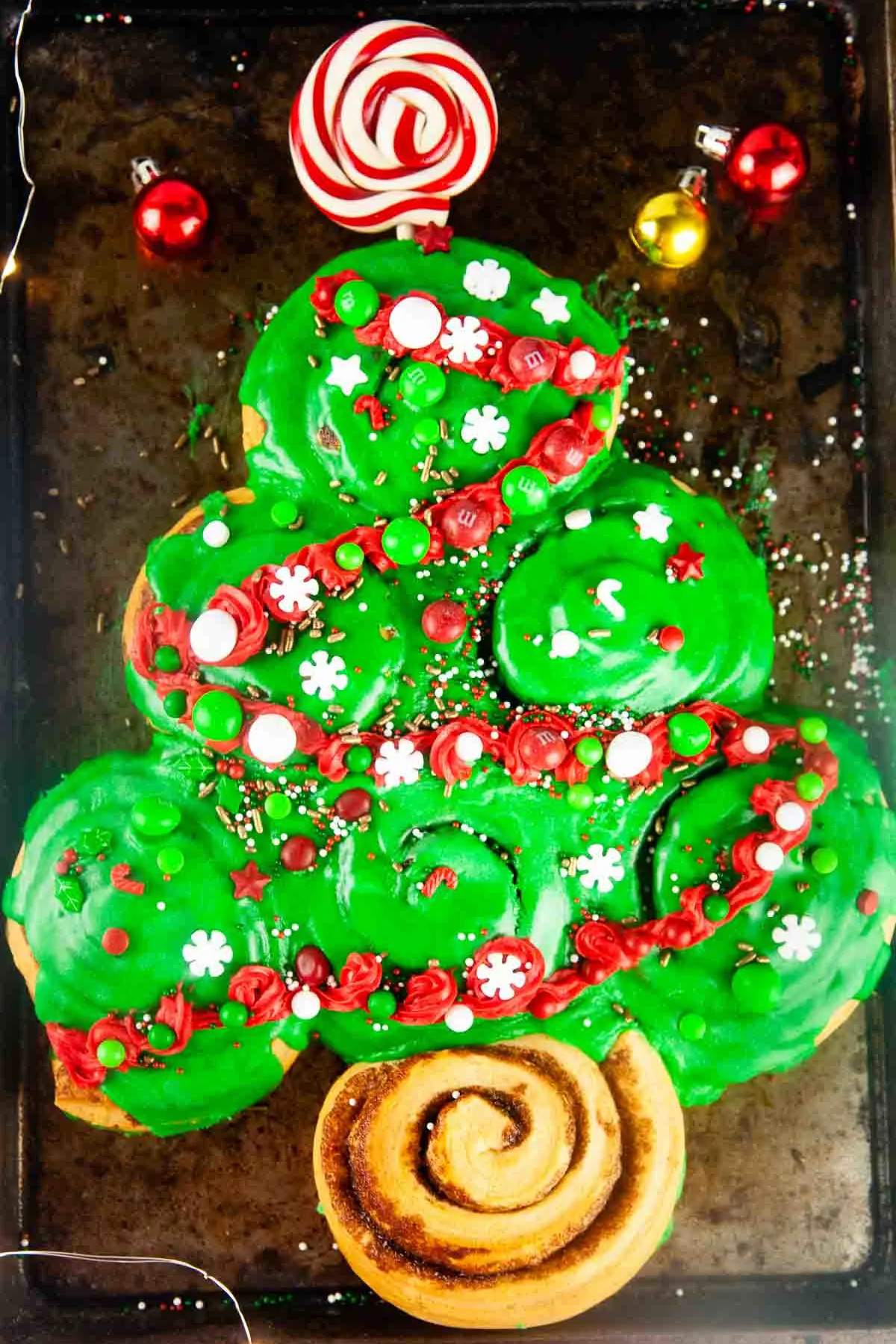 Christmas tree made with cinnamon rolls, topped with green icing and candy.