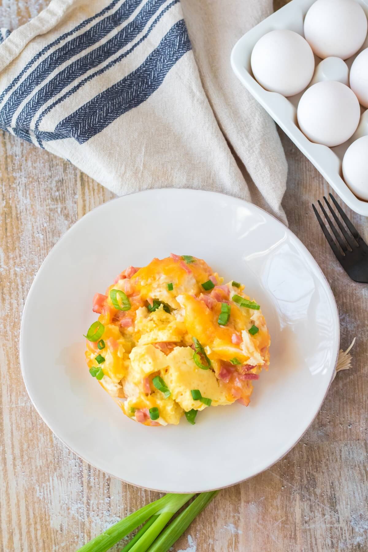 serving of slow cooker breakfast casserole on plate with carton of eggs in the background.