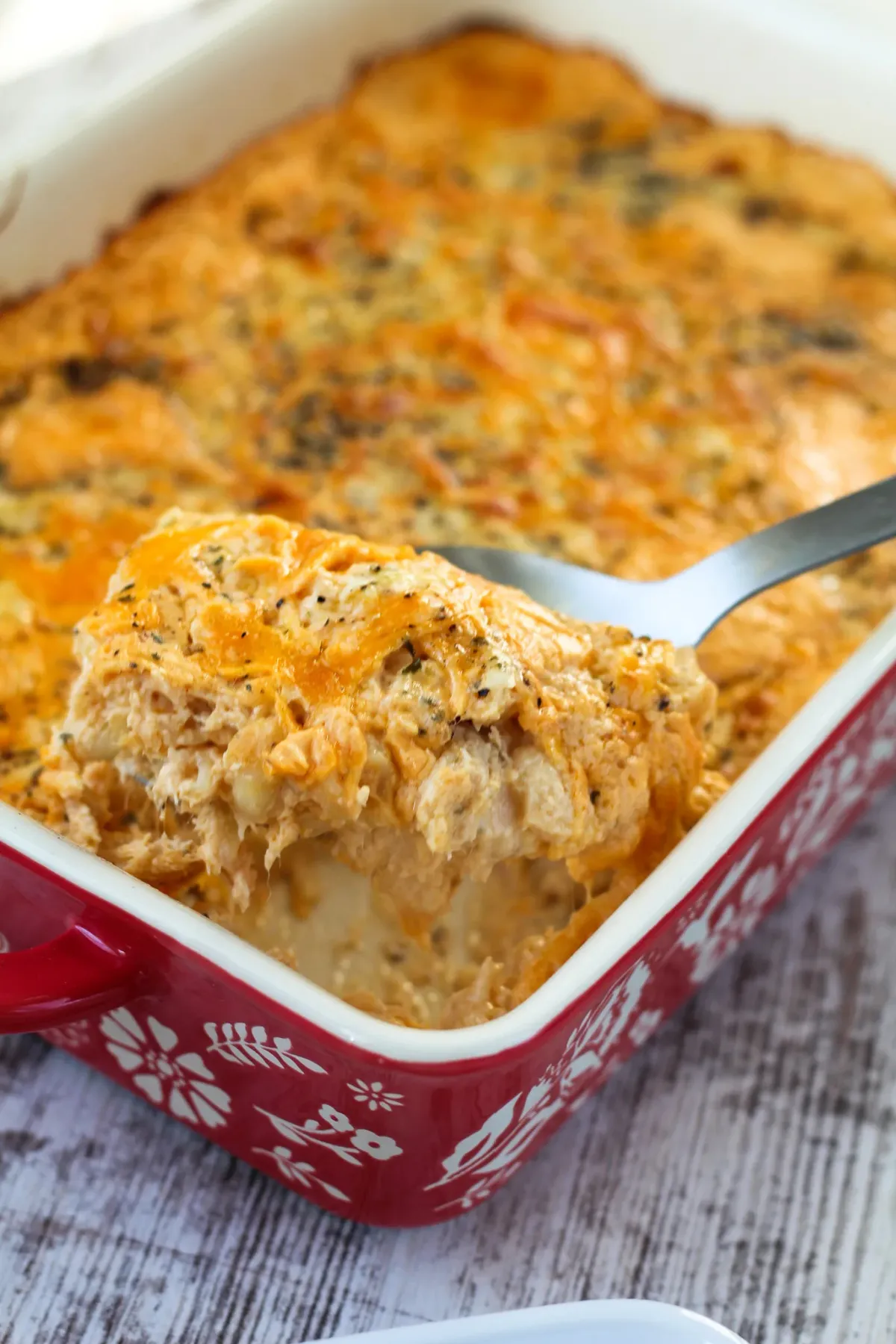 buffalo chicken mac and cheese in a red casserole dish with white flowers.