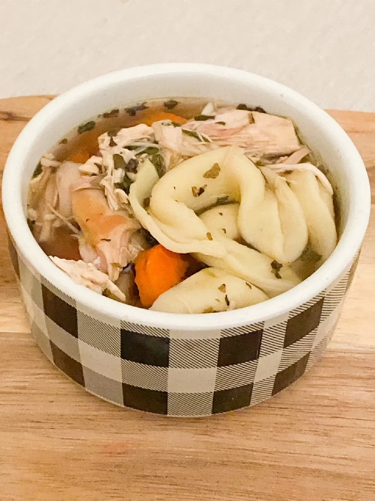 chicken tortellini soup in bowl with carrots and shredded chicken.