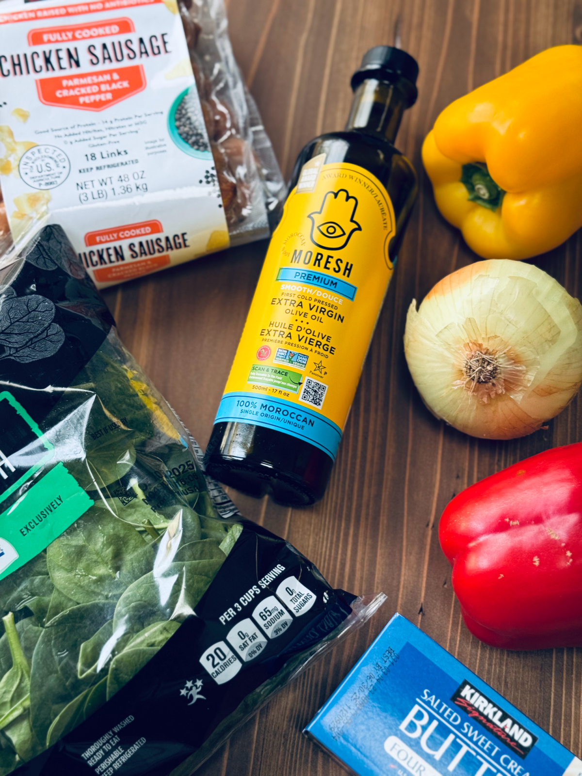 ingredients for chicken sausage stir fry, including Moresh olive oil, bell peppers, onion and Kirkland's chicken sausage.