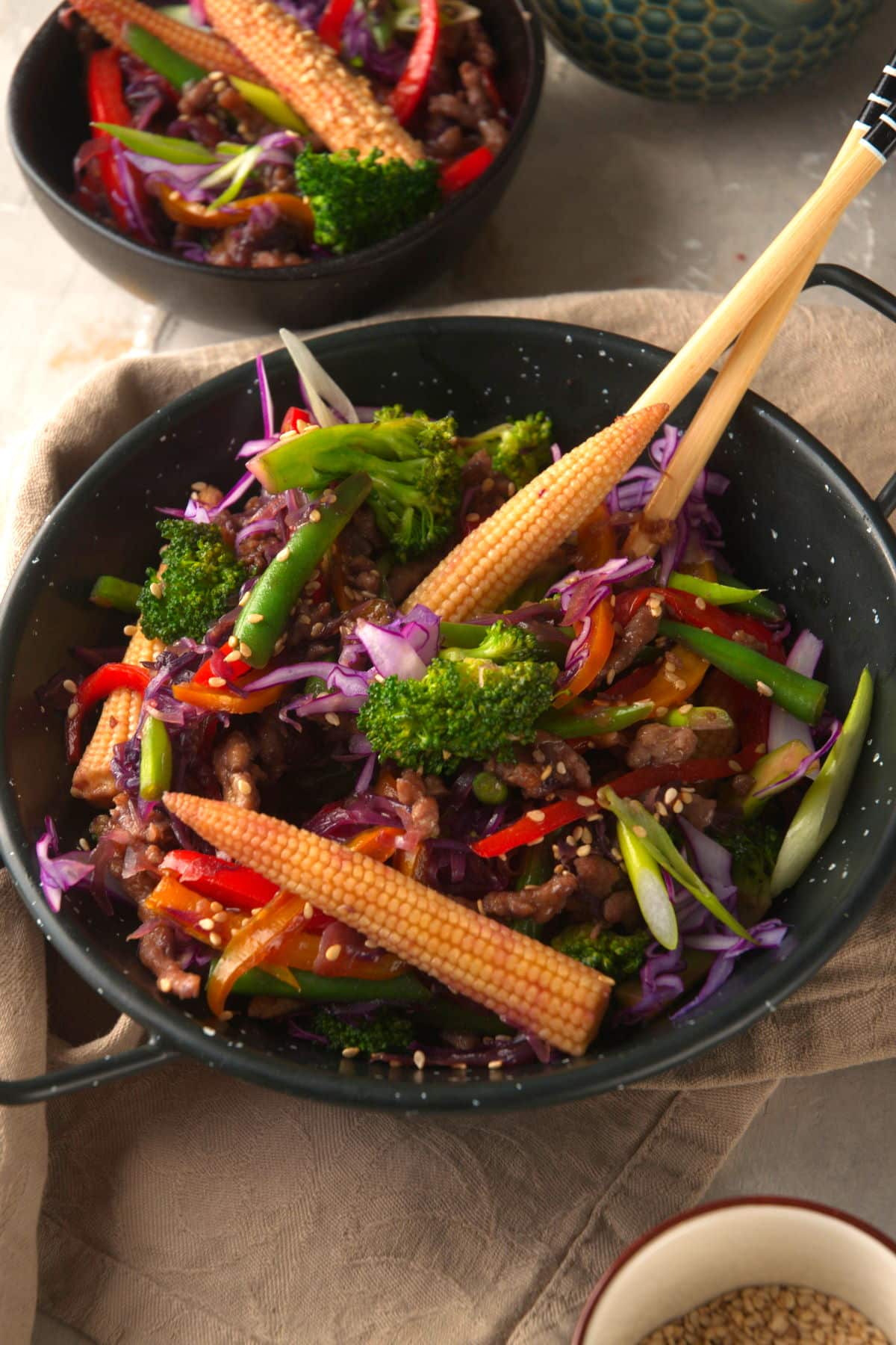 ground beef stir fry with colorful vegetables in black bowl with chop sticks.