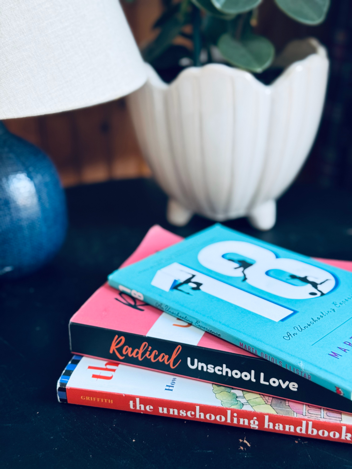 unschooling books spread out on table, with lamp and plant in background.