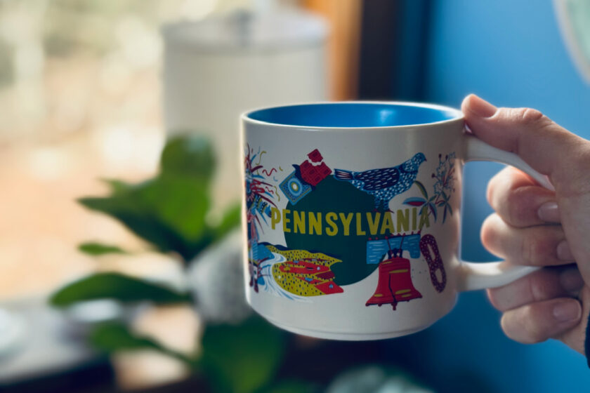 Pennsylvania Starbucks mug in focus with plant and lamp in background.