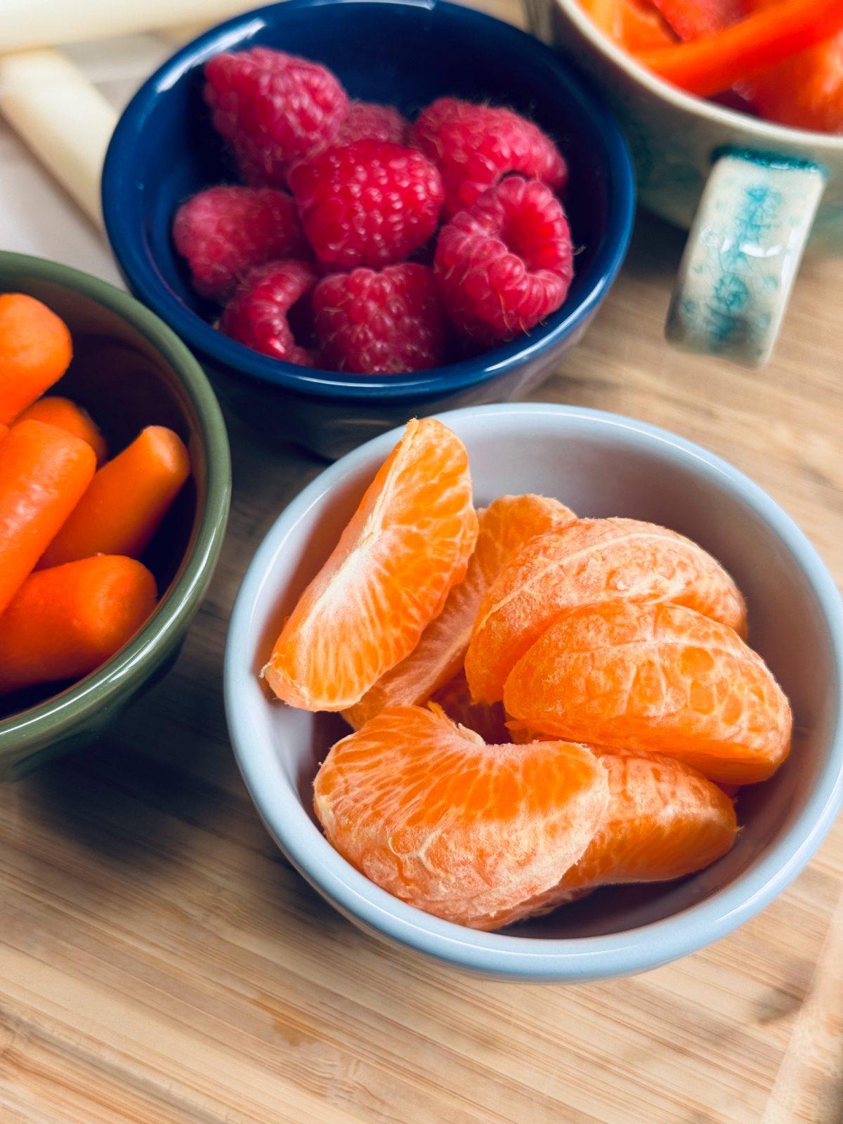 mandarin orange slices and raspberries in tiny blue bowls.