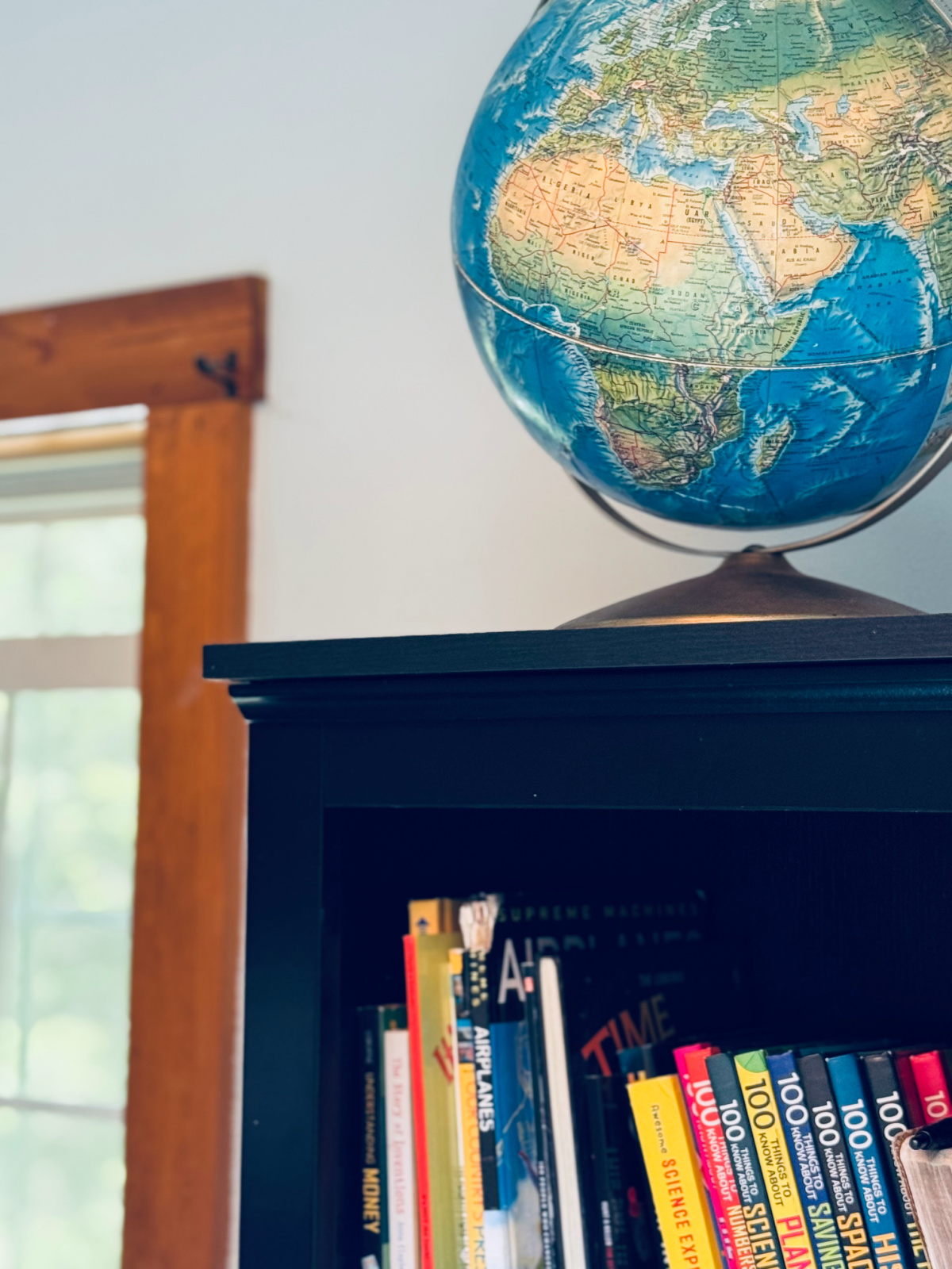 Globe on top of black bookshelf.