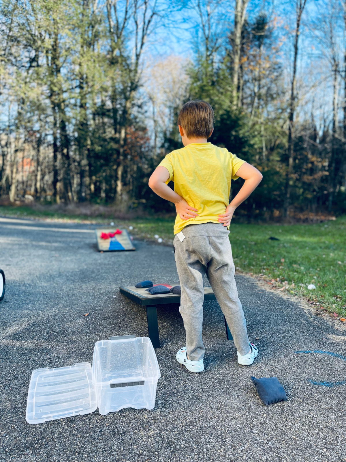 child standing outside playing cornhole.